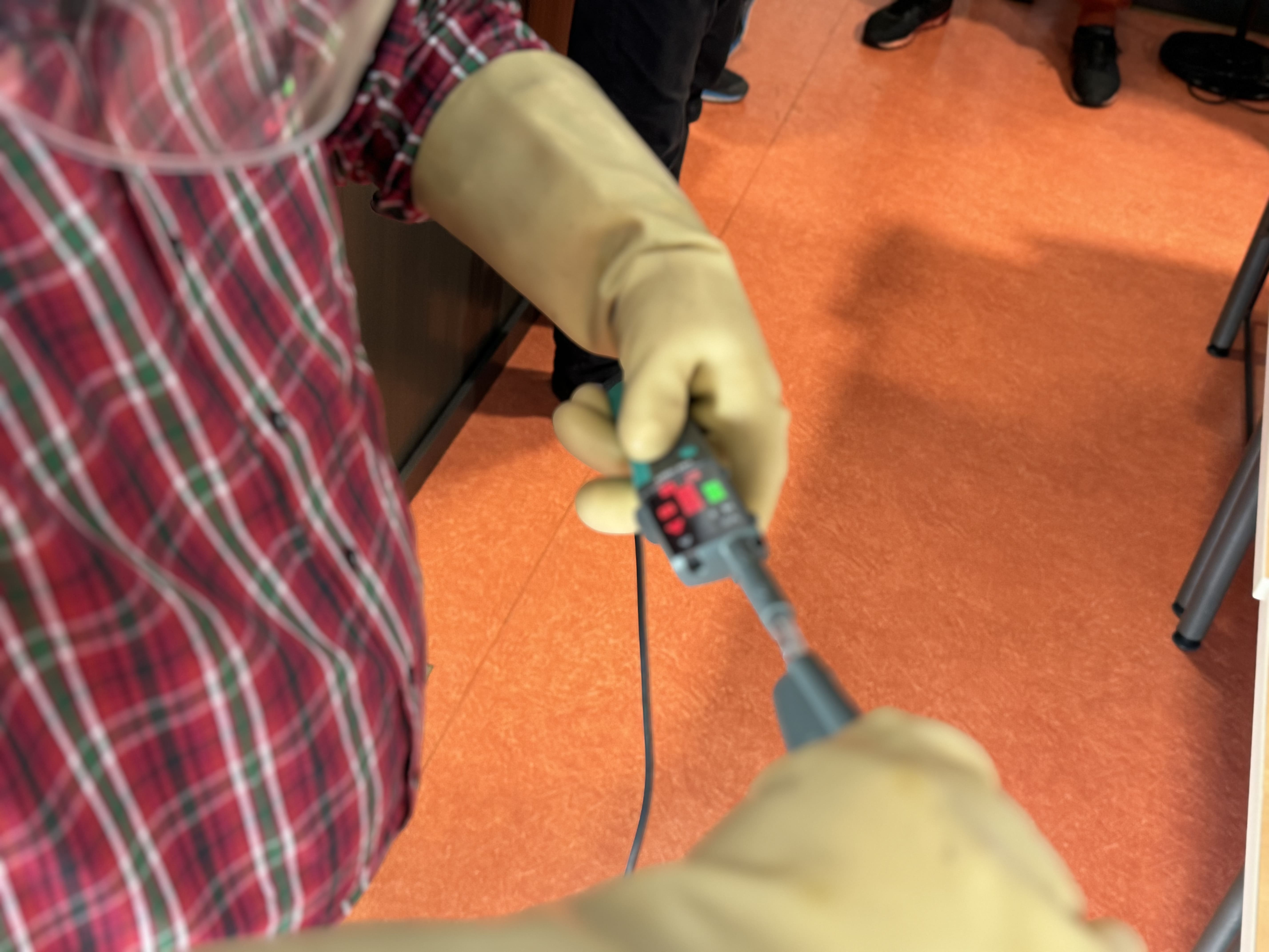 appareil-mesure-electrique-gants Personne utilisant un appareil de mesure électrique avec des gants.
