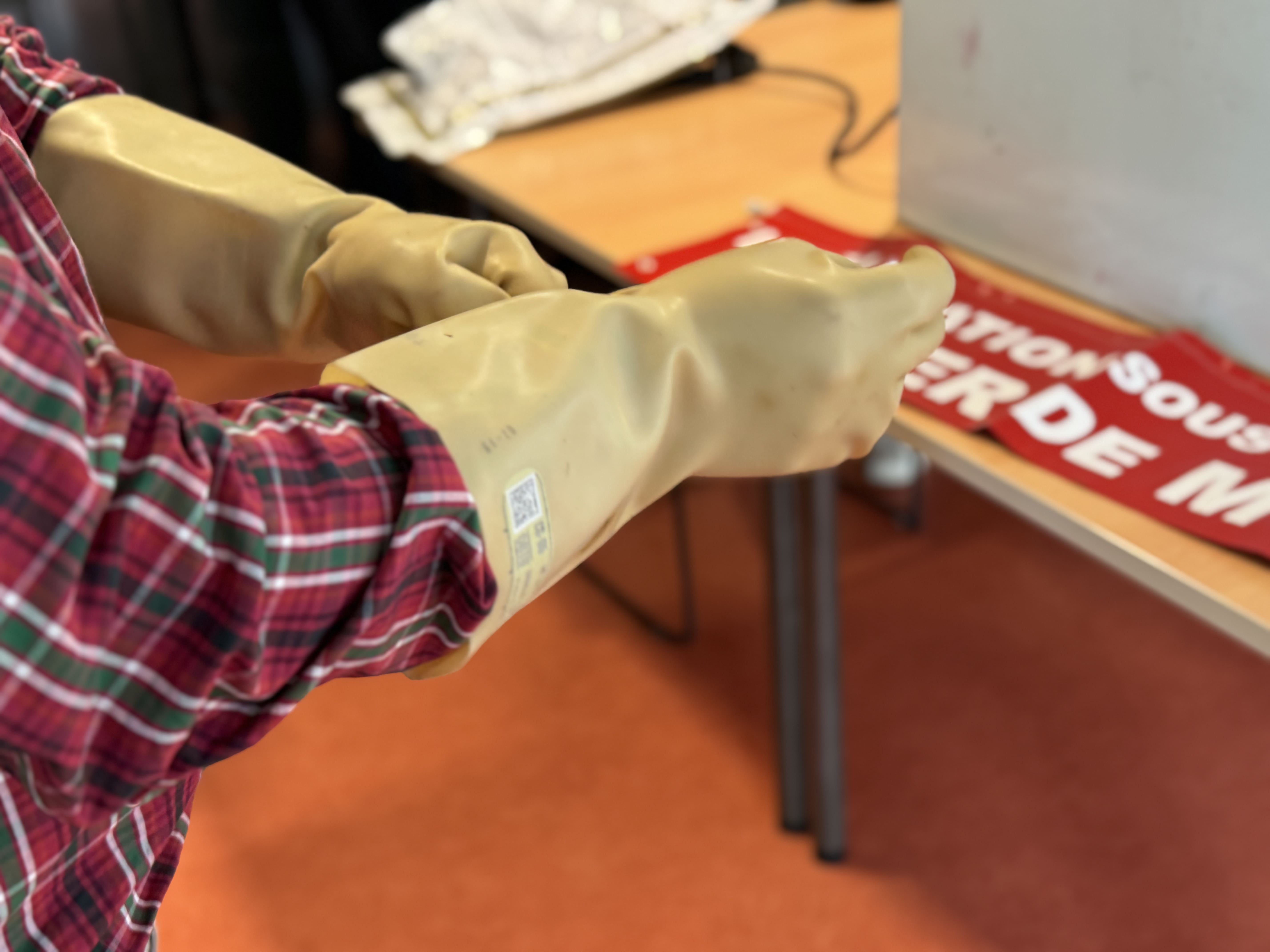 gants-habilitation-électrique Personne mettant des gants en caoutchouc pour sécurité électrique