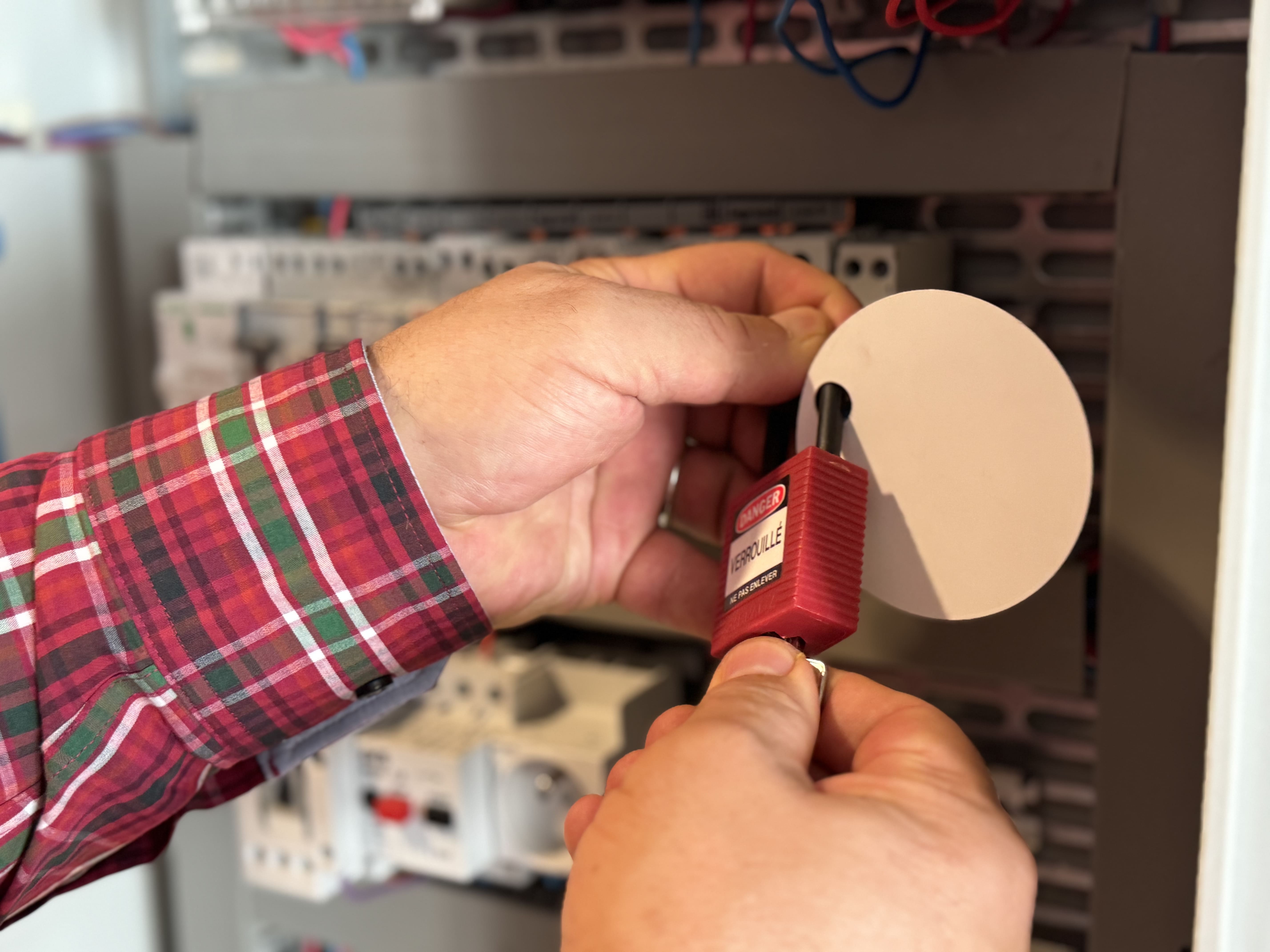 Homme utilisant un cadenas sur un panneau électrique